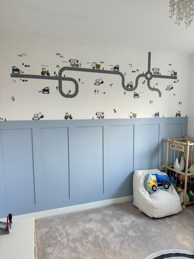 Happy toddler playing in a nursery decorated with colorful truck, tractor, and digger wall stickers, sparking creativity and joy